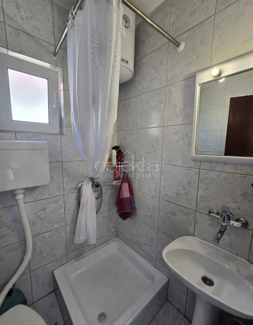 Manje kupatilo sa tuš kabinom, umivaonikom i prozorom.