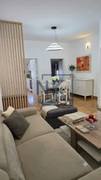 Living room with sofa, dining area and wooden partition. - image 2