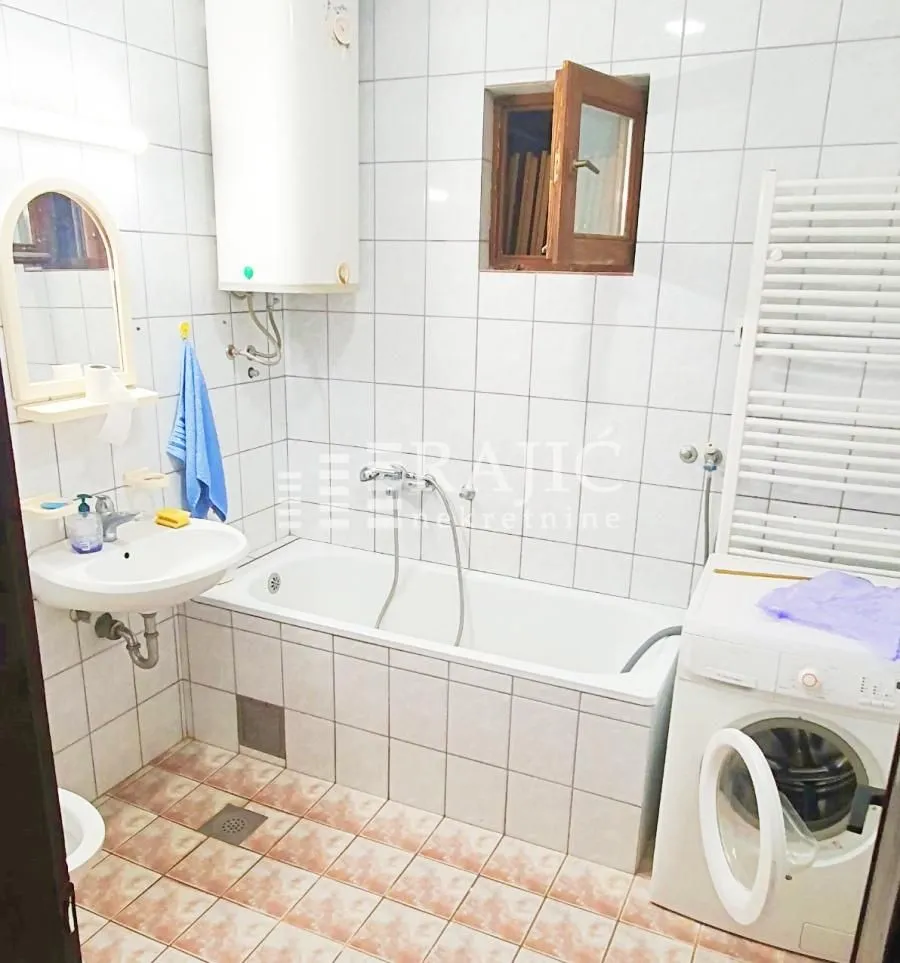Small bathroom with a bathtub, washbasin, and washing machine.