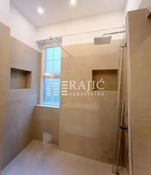 Modern bathroom with a walk-in shower tiled in beige tones. - image 17