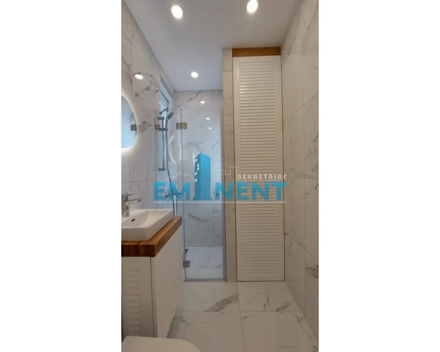 Modernly equipped bathroom with a walk-in shower and marble tiles.