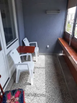 A narrow balcony with two plastic chairs and a small table. - image 9