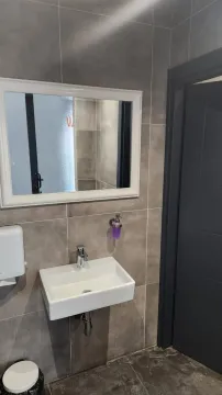 Small bathroom with a washbasin, mirror and gray wall tiles. - image 6