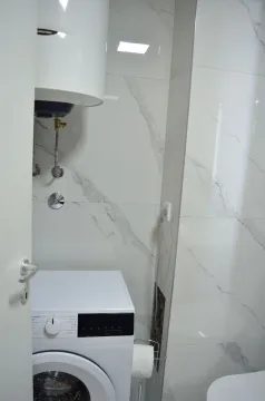 Kupatilo sa bijelim mermernim pločicama, veš mašinom i bojlerom. - image 3