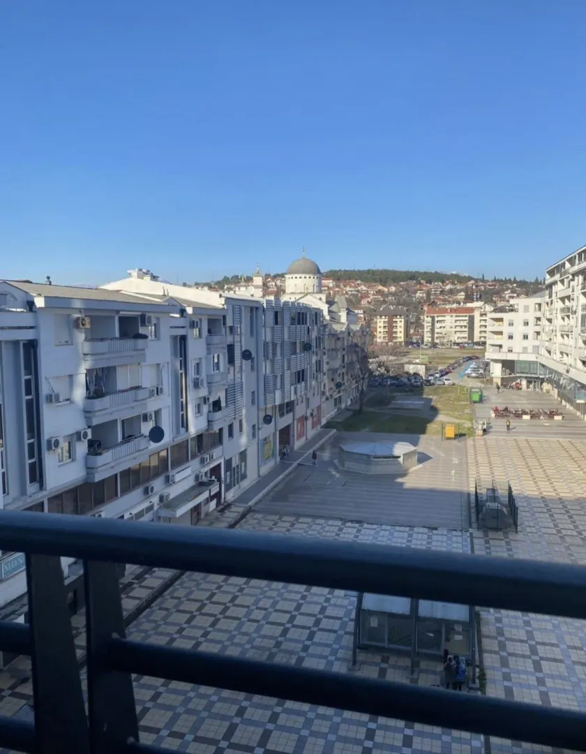 View from a balcony overlooking a city square and residential buildings.