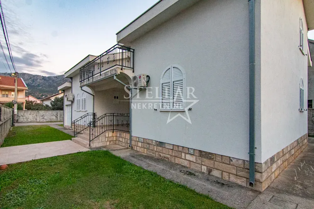 Exterior view of the house with a yard and a balcony.