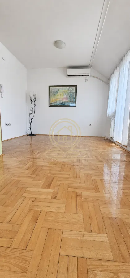 Prazna soba sa parketom na podu i klima uređajem na zidu.