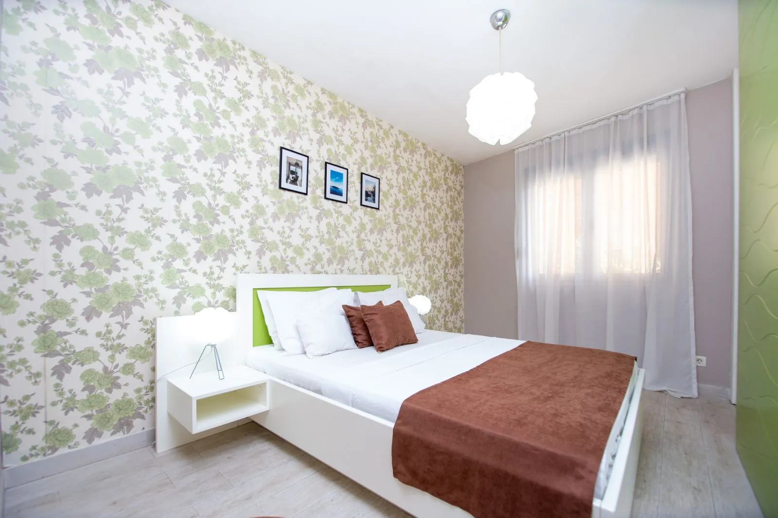 Furnished bedroom with a double bed and patterned wallpaper.