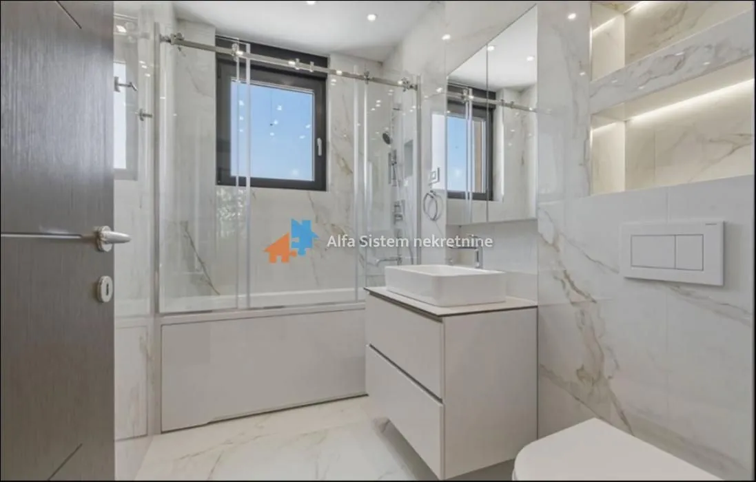 Modern bathroom equipped with a shower cabin, vanity, and white marble-effect ceramic tiles.