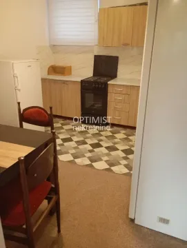 Manja kuhinja sa drvenim elementima i trpezarijskim stolom u prednjem delu. - image 3