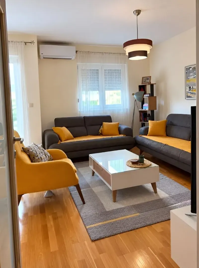 Furnished living room with sofa set, coffee table and parquet flooring.