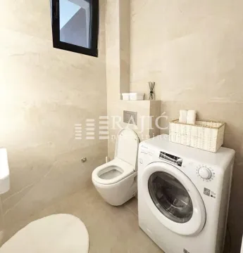 Small bathroom with a washing machine and a built-in toilet bowl. - image 8