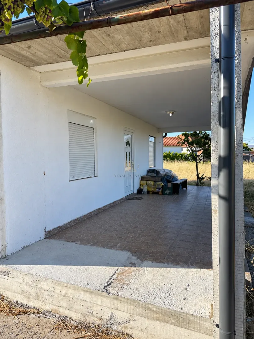 Covered terrace in front of the house entrance with tiled flooring.