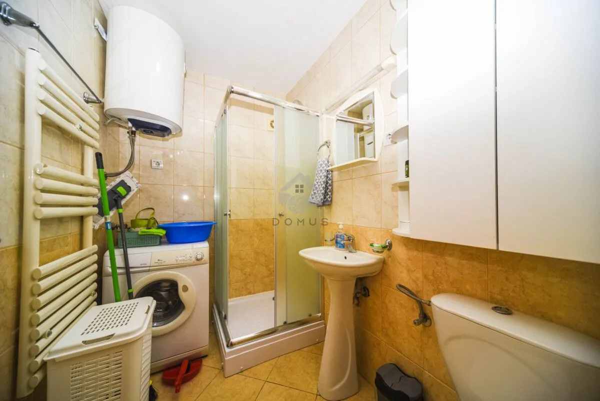 Bathroom equipped with a shower cabin, washbasin, toilet, and washing machine.