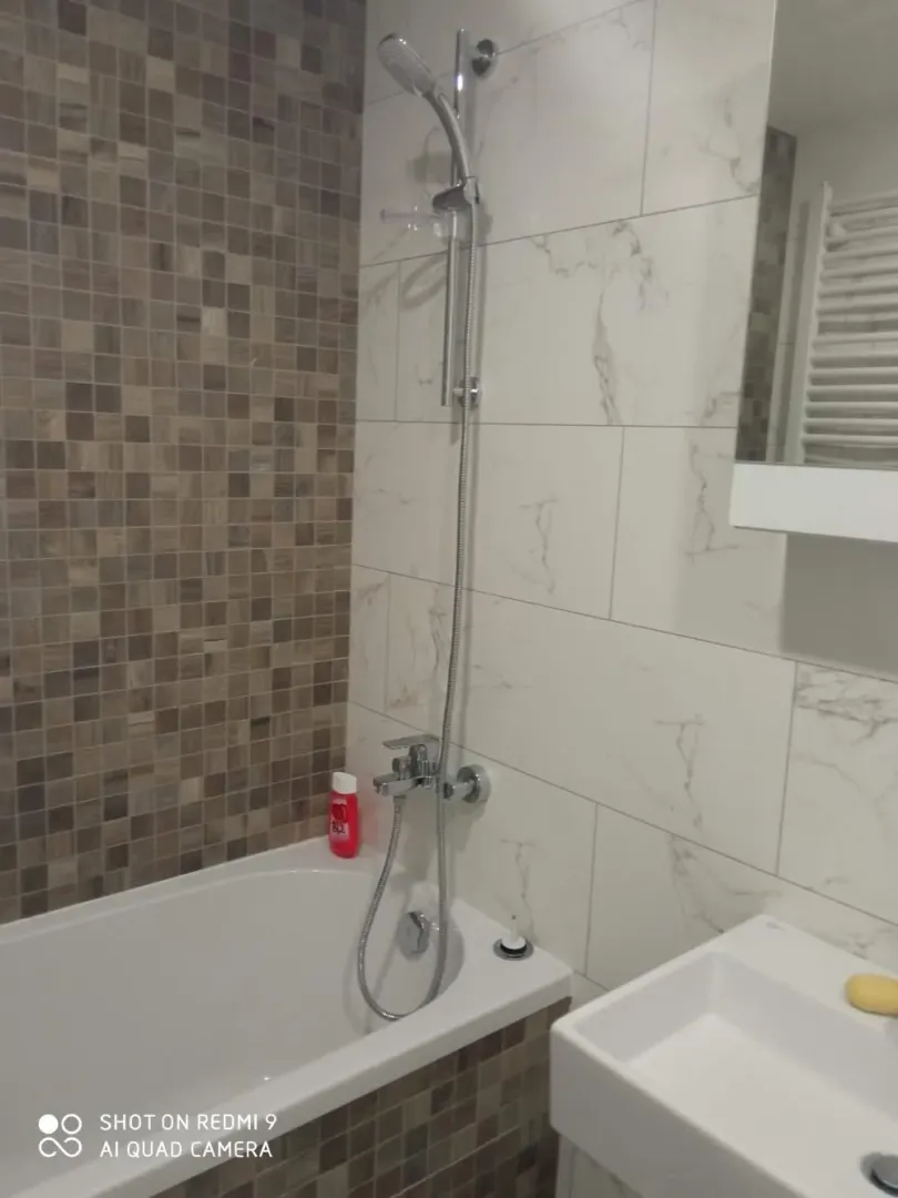 Bathroom with a bathtub, shower set and washbasin.