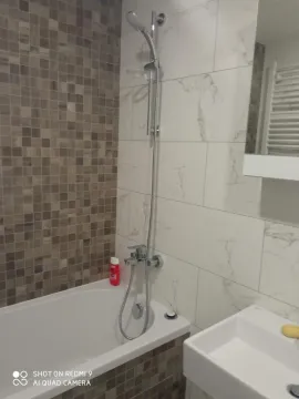 Bathroom with a bathtub, shower set and washbasin. - image 9