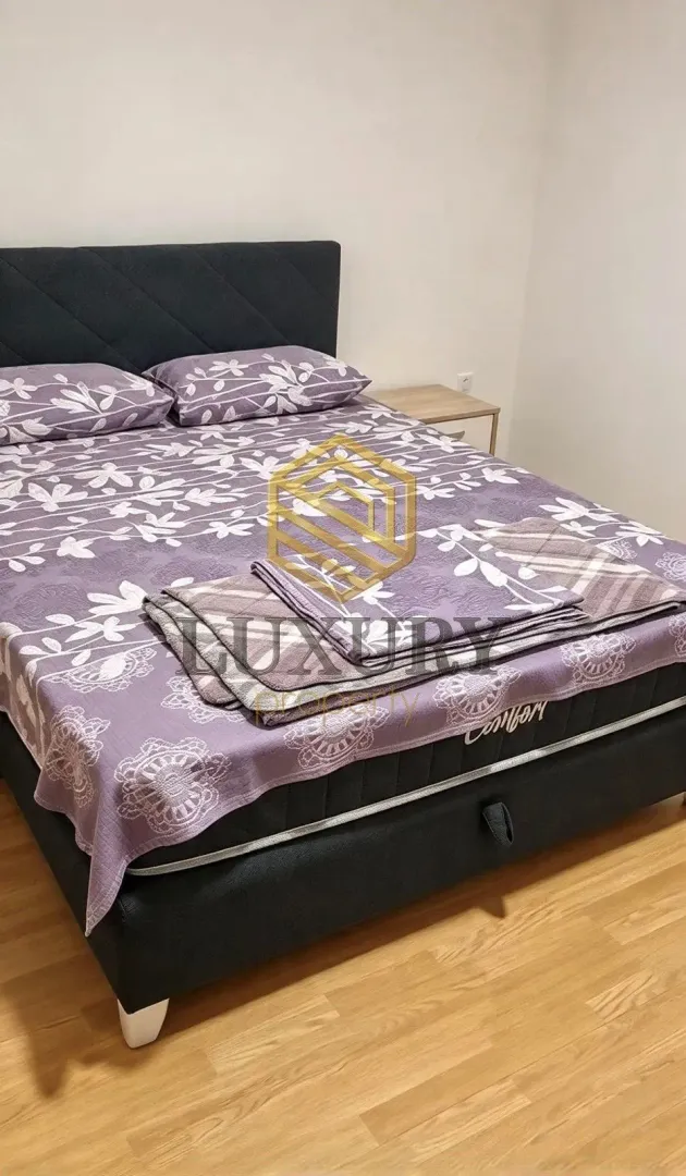 Namještena spavaća soba sa bračnim krevetom.