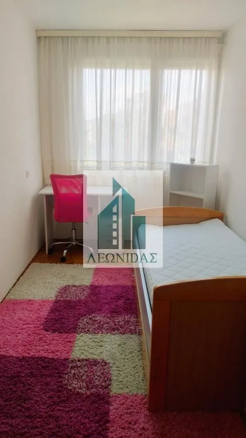 Children's bedroom with a bed, desk, and a colorful rug.