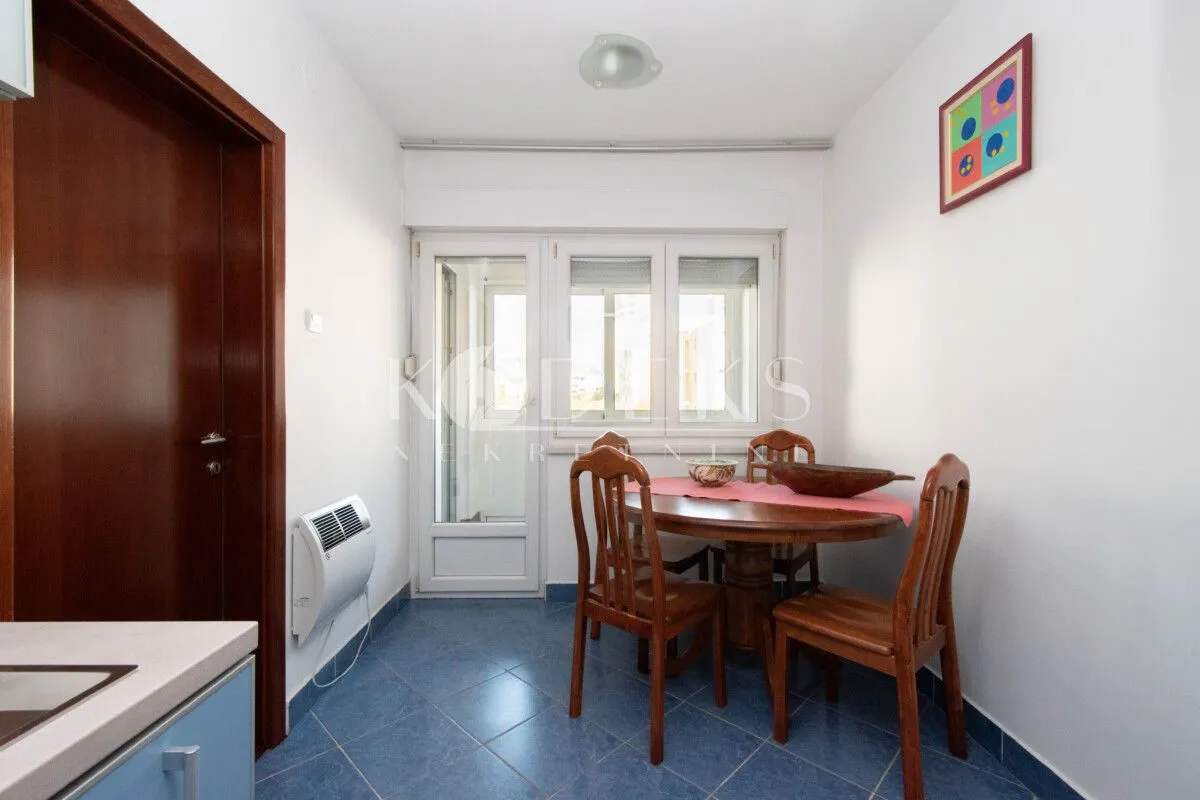 Dining area with a wooden table and chairs, blue floor tiles, and access to the terrace.
