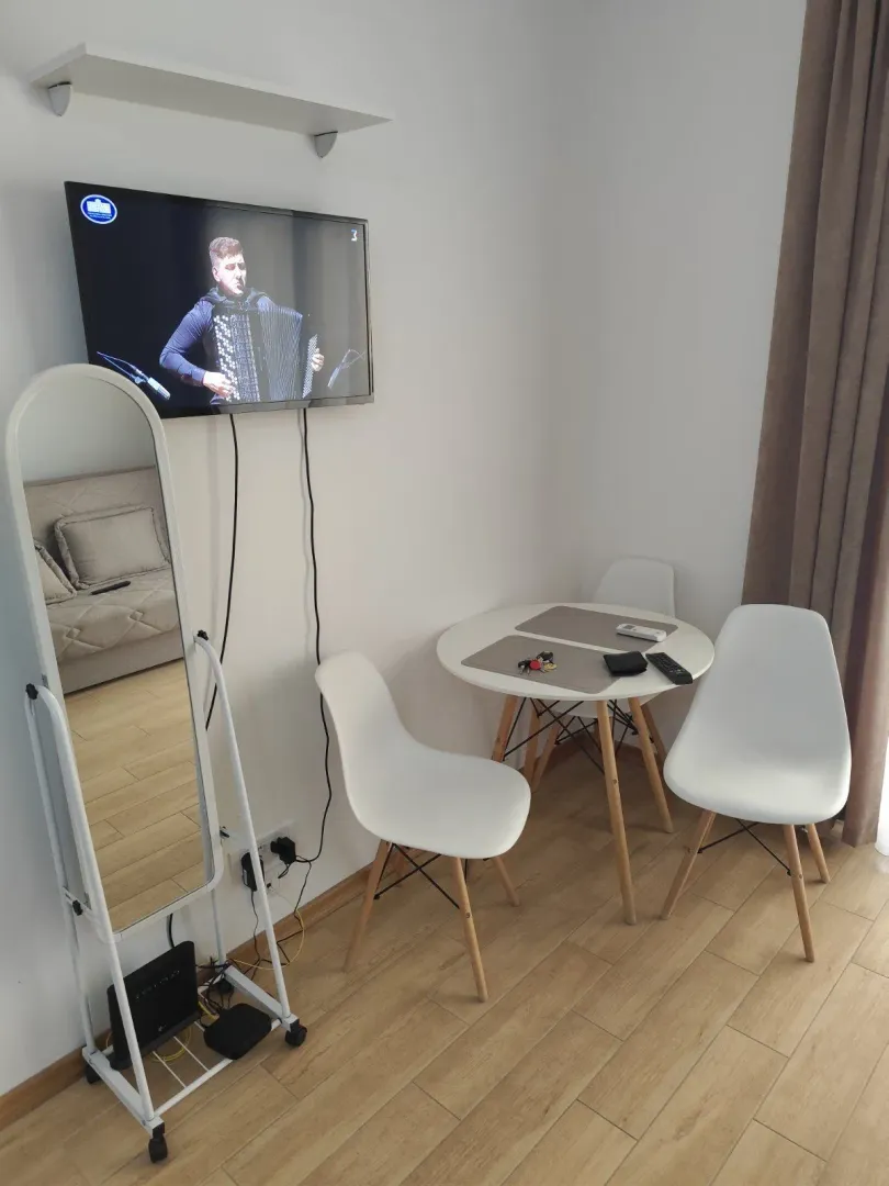 Small dining table with chairs and a wall-mounted TV in the living room.