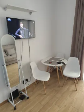 Small dining table with chairs and a wall-mounted TV in the living room. - image 3