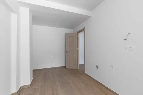 Prazna soba sa bijelim zidovima, drvenim podom i otvorenim vratima. - image 11