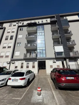 Facade of a modern apartment building with an entrance, balconies, and parked cars in front. - image 7