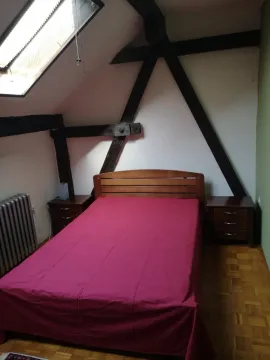 Attic bedroom with a double bed, roof window and wooden beams. - image 5