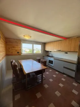 Moderna kuhinja sa trpezarijskim stolom i drvenim oblogama na zidu. - image 3