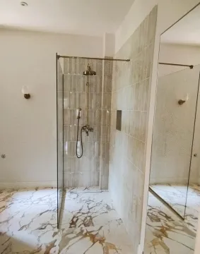 Modern bathroom with a walk-in shower and marble floor. - image 12