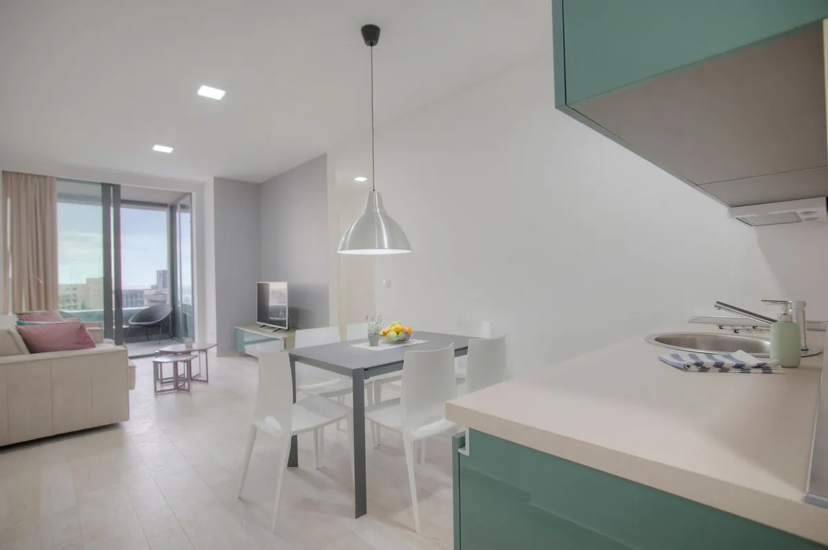 Modern kitchen with a dining area and living room in light tones.
