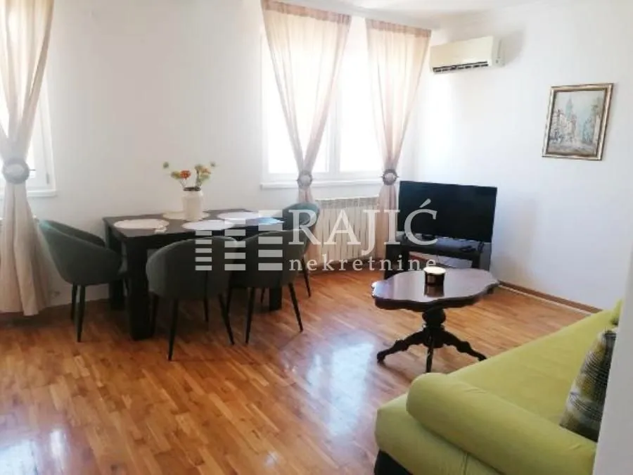 Bright living room with a dining area, wooden flooring, and furniture.