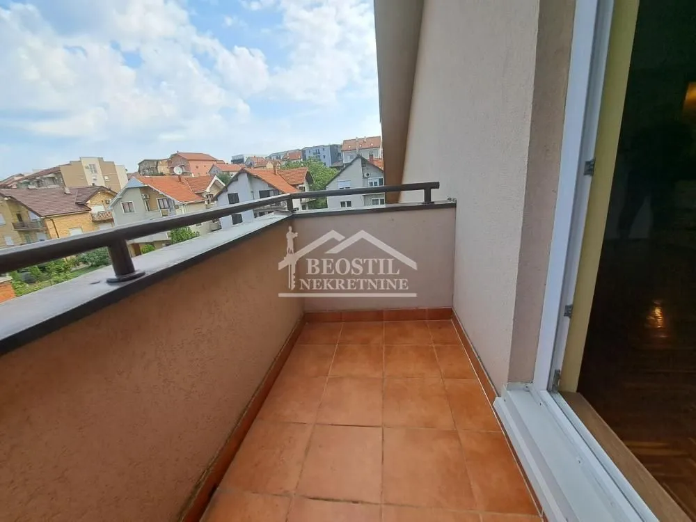 Otvoreni balkon sa podnim pločicama i pogledom na naselje.