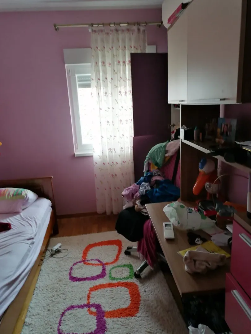 Dječija soba sa krevetom, radnim stolom i ružičastim zidovima.