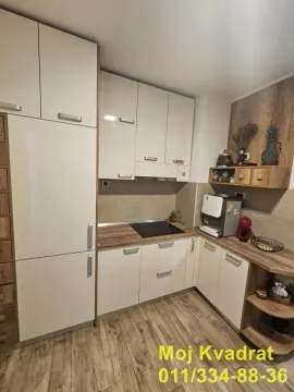Manja opremljena kuhinja sa drvenim radnim površinama i belim elementima. - image 4