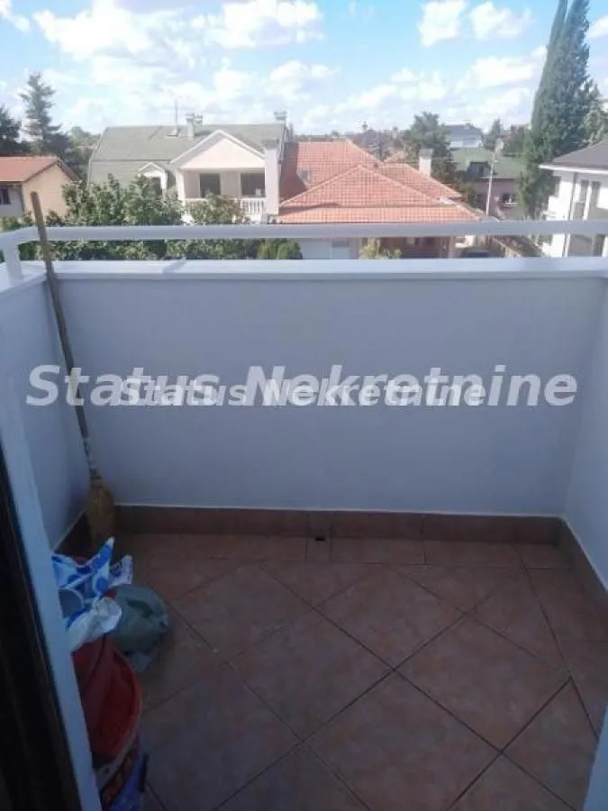 Manji popločani balkon sa pogledom na naselje i okolne kuće.