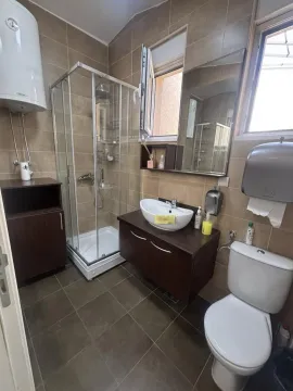 Bathroom equipped with a shower cabin, washbasin, toilet, and water heater. - image 6