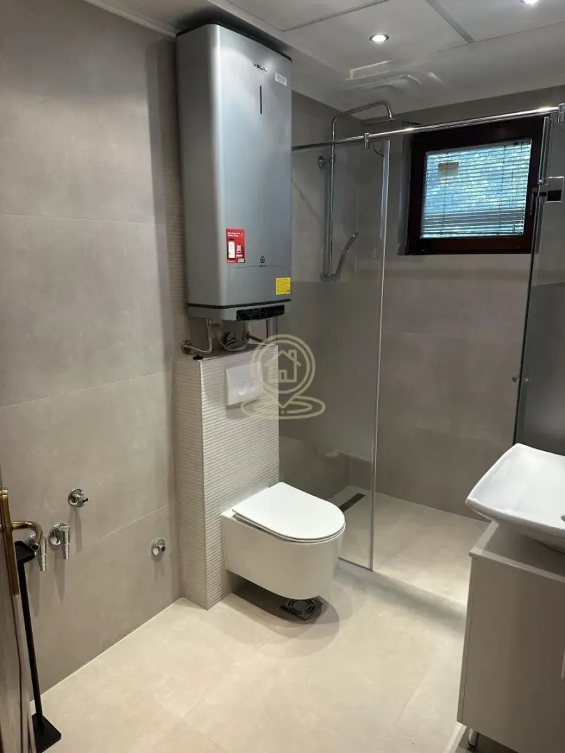Modern bathroom equipped with a walk-in shower, wall-hung toilet, and water heater.