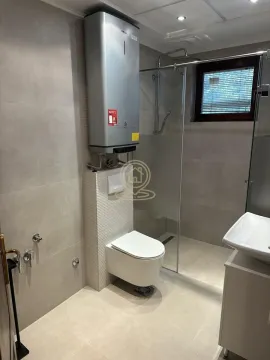 Modern bathroom equipped with a walk-in shower, wall-hung toilet, and water heater. - image 10