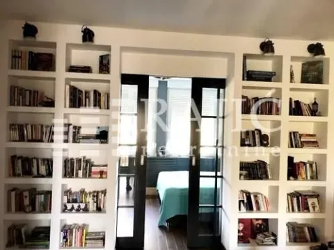 Living room with built-in bookshelves and a view into the bedroom. - image 5