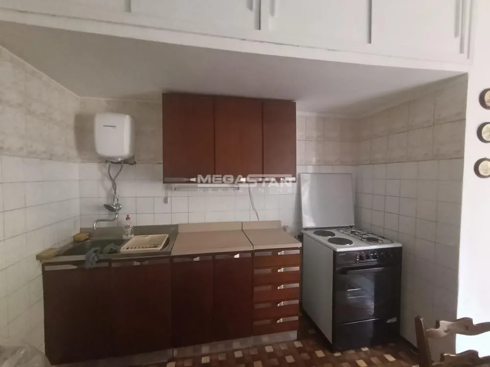 Older kitchen with sink, countertops, and a stove.