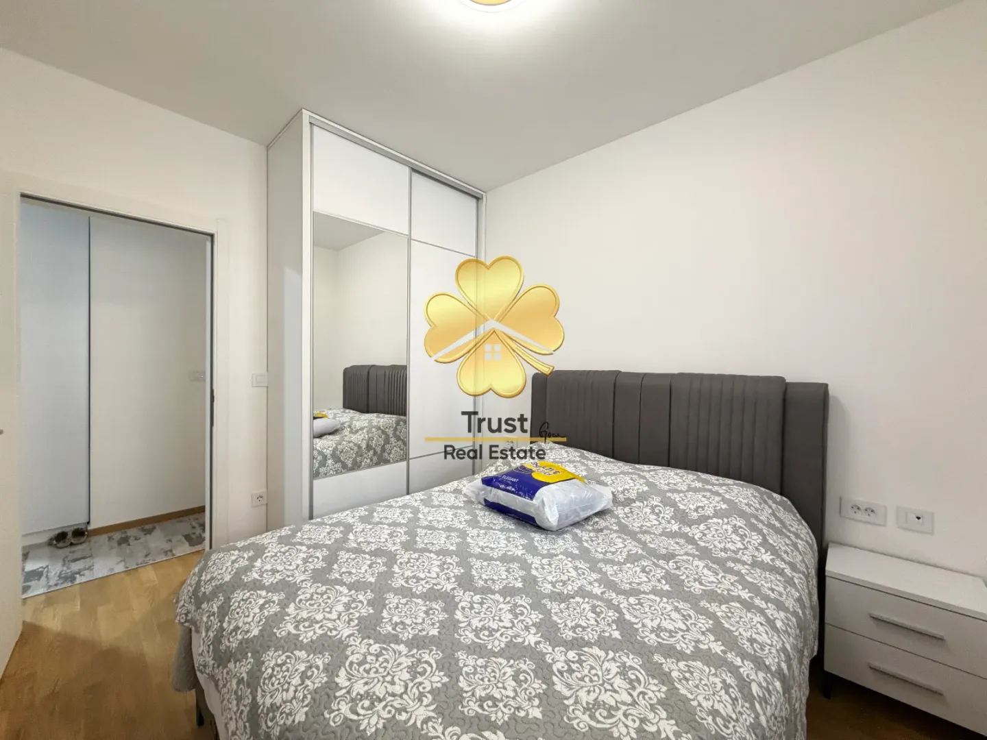 Furnished bedroom with a large double bed and a built-in wardrobe with a mirror.