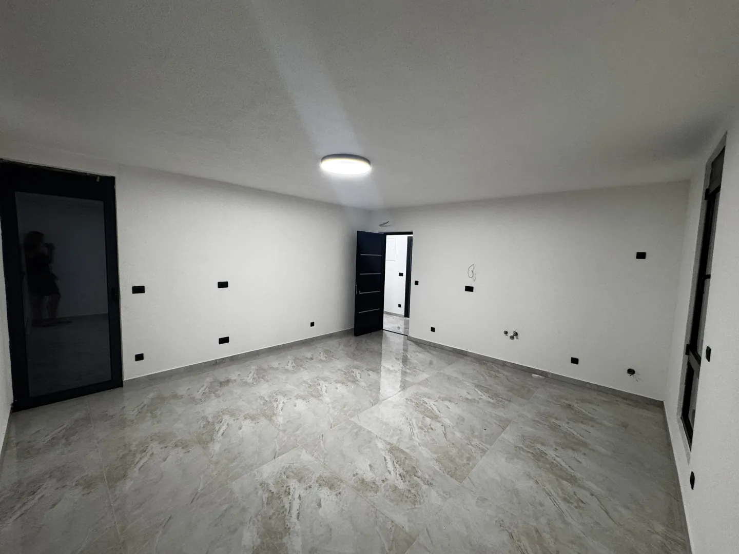 Empty room with light walls, glossy tiles, and built-in lighting.