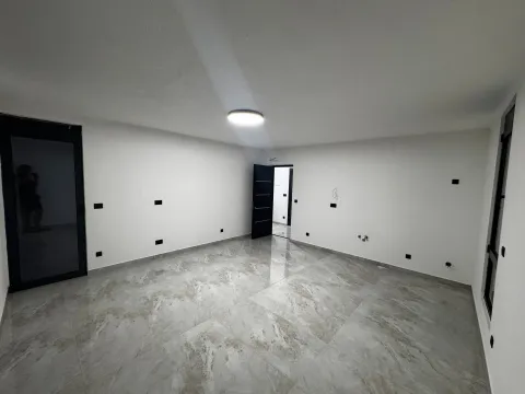 Empty room with light walls, glossy tiles, and built-in lighting. - image 7