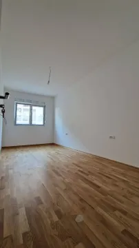 Prazna soba sa parketom i jednim prozorom. - image 2