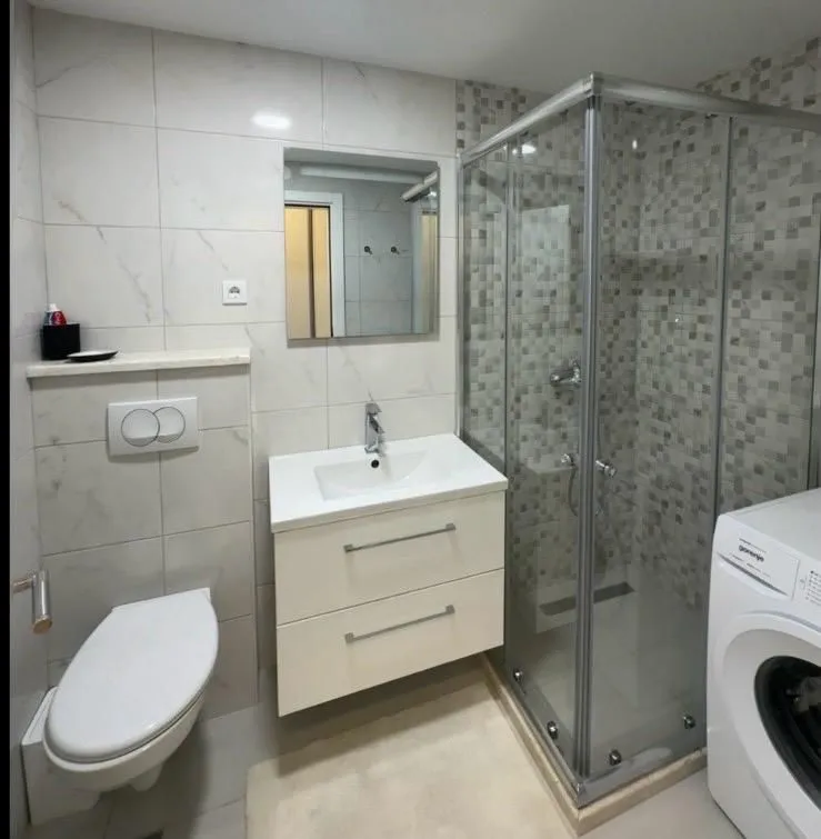 Modern bathroom equipped with a shower cabin, vanity unit, and washing machine.