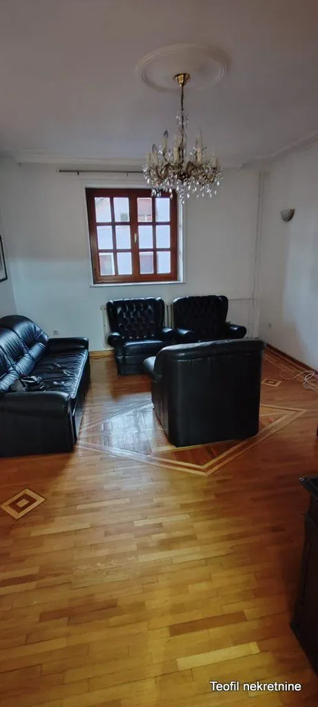 Living room with seating furniture and wooden parquet flooring.