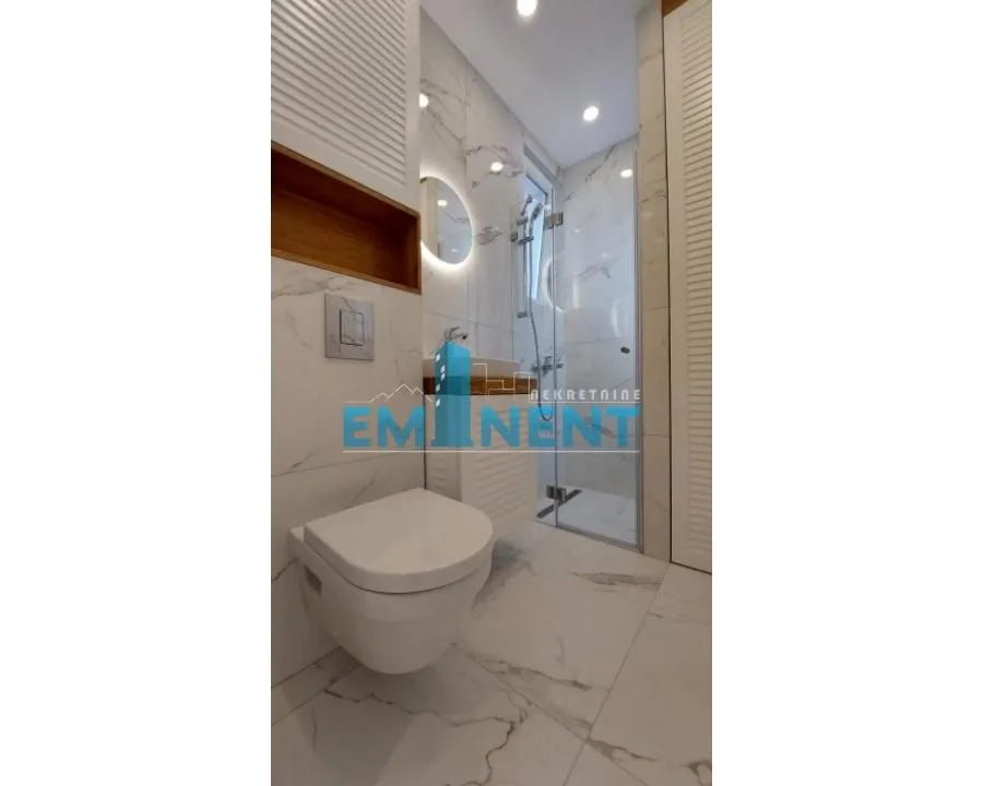 Modernly equipped bathroom with a walk-in shower and marble tiles.