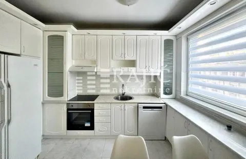 White kitchen with built-in appliances and a window. - image 15