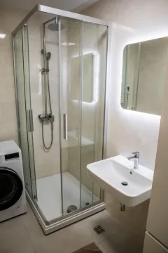 Modern bathroom with a shower cabin, washbasin, and washing machine. - image 5